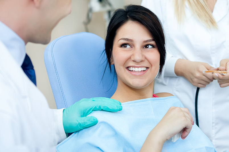 Male dentist, his assistant and female patient smiling in dental practice